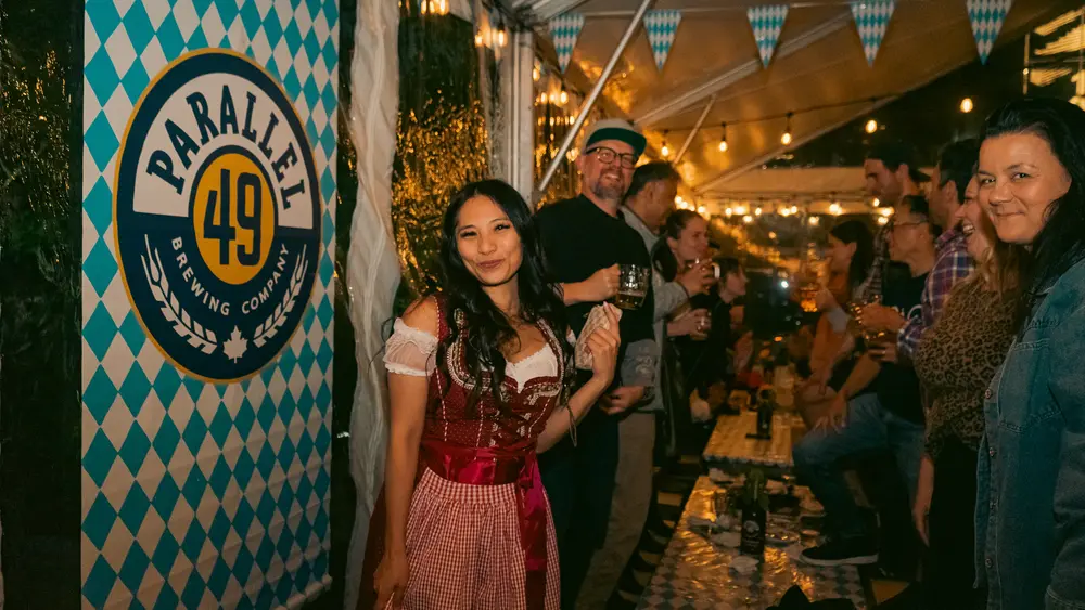 A guest in a dirndl in front of the Parallel 49 blue-and-white checked backdrop