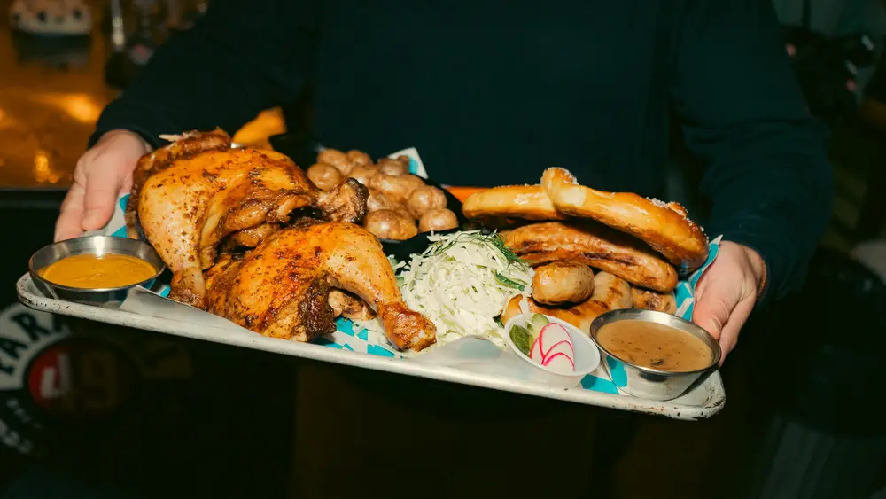 A platter of roast chicken, sausages, a pretzel, potatoes and sauerkraut