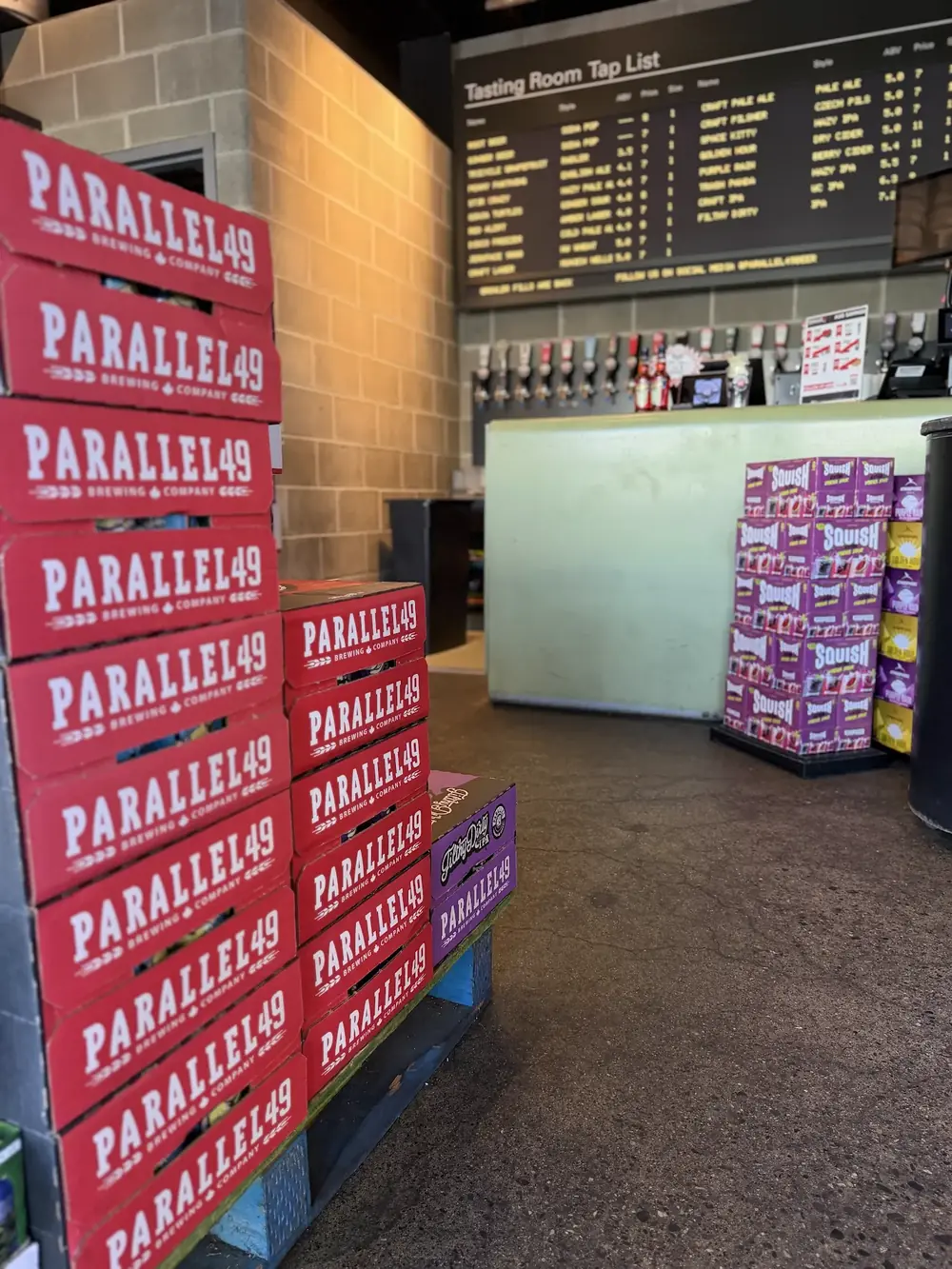 Stacked Parallel 49 cases beside the tasting room bar and tap list